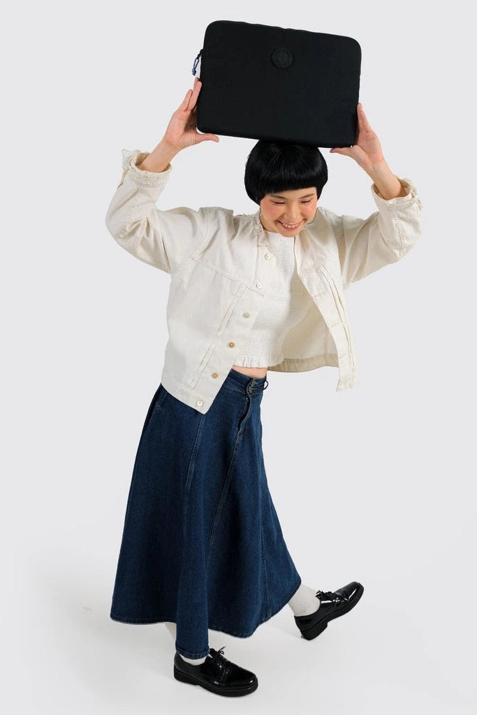 Person holding a black laptop sleeve by Exsport Bag above their head against a white background