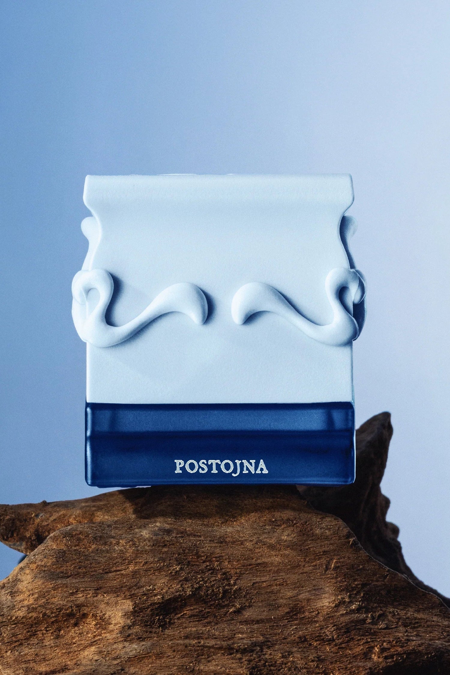 Ceramic container with wavy design on a blue background, featuring the label 'POSTOJNA' by Saff & Co.