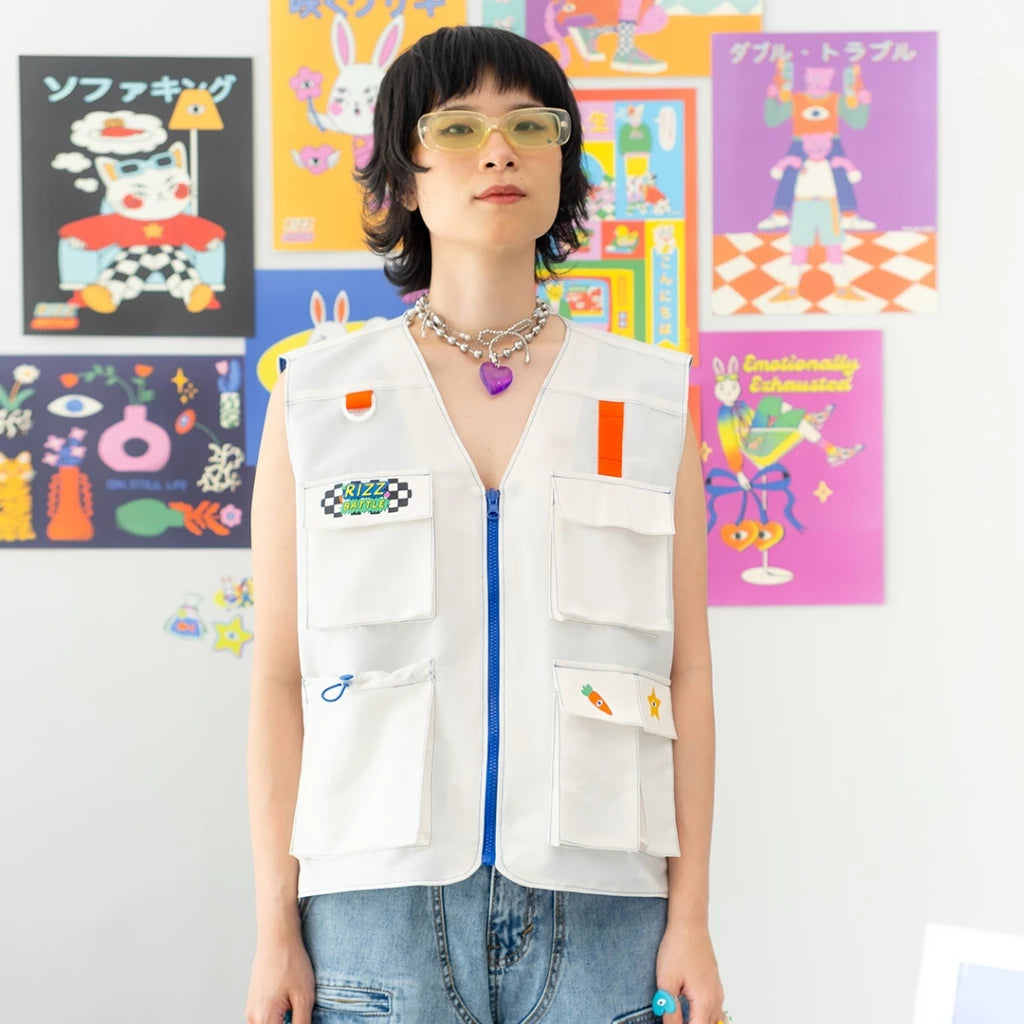 A person wearing a white vest with various colorful patches and blue zipper, named Game On Vest from Oh.Irv, standing in a room with colorful wall art.
