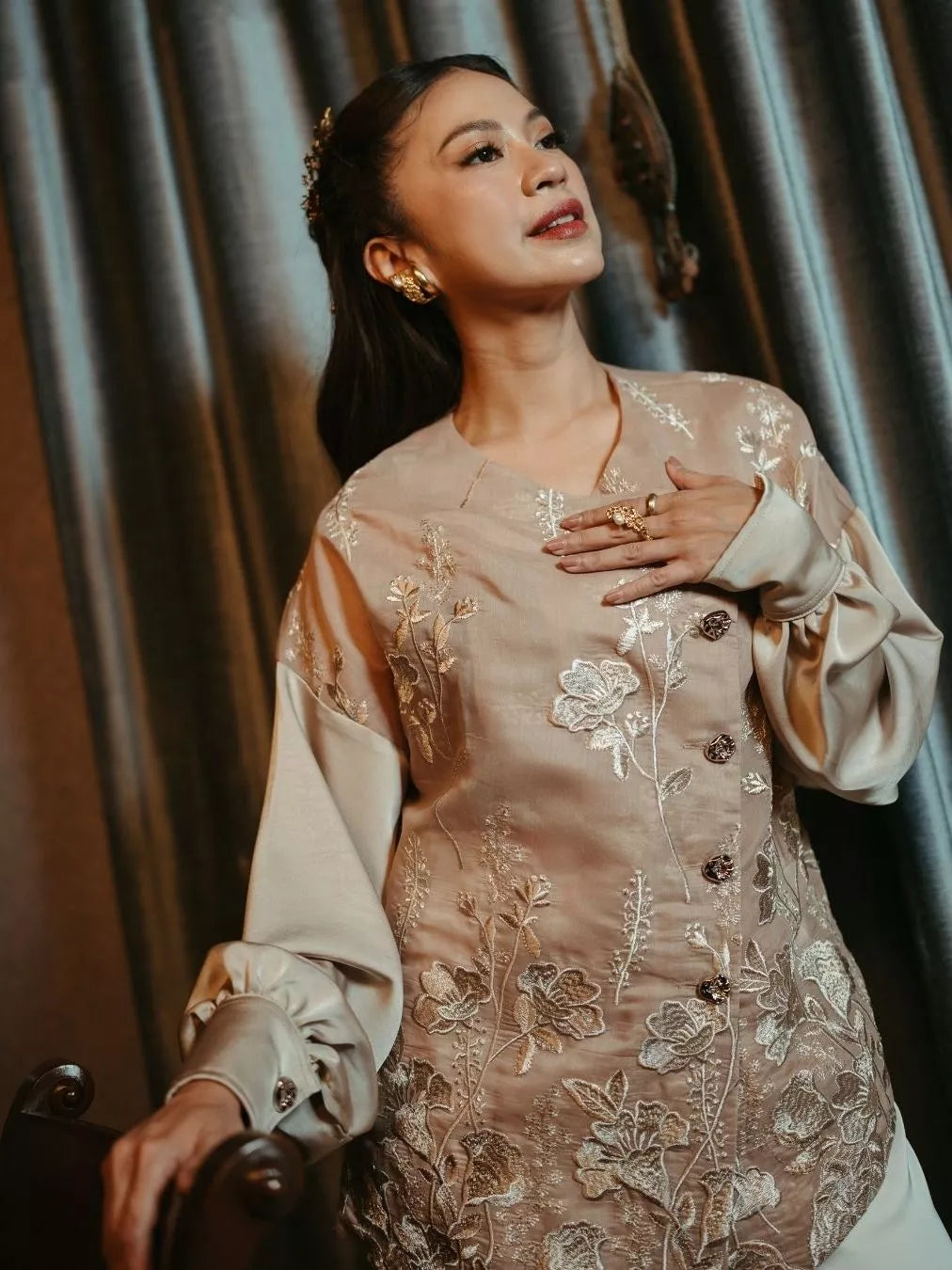 Woman wearing a traditional embroidered outfit with floral patterns by LR Studio.