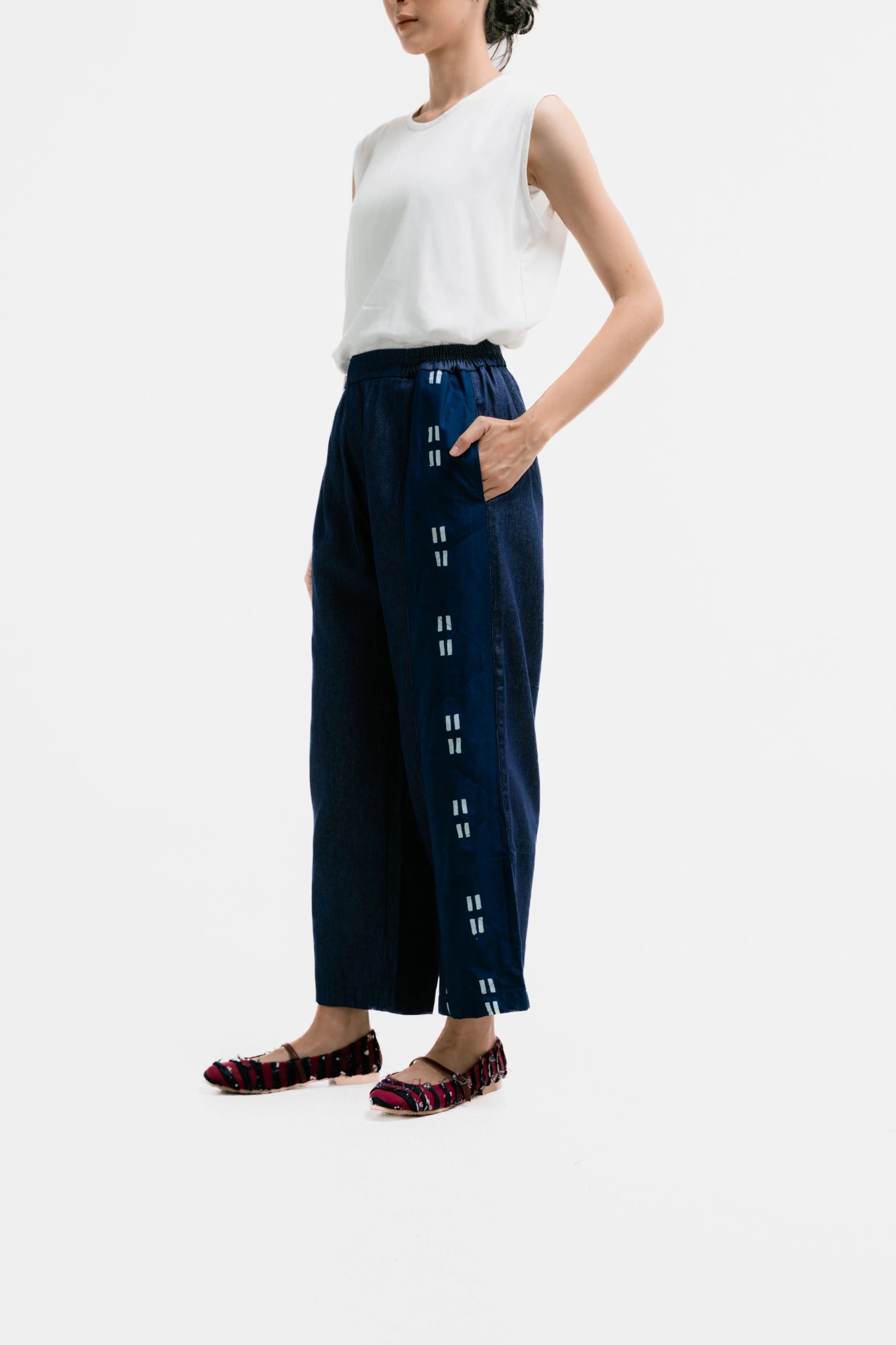 Person wearing a white top and Gayatri Denim Pants from Damakara on a white background