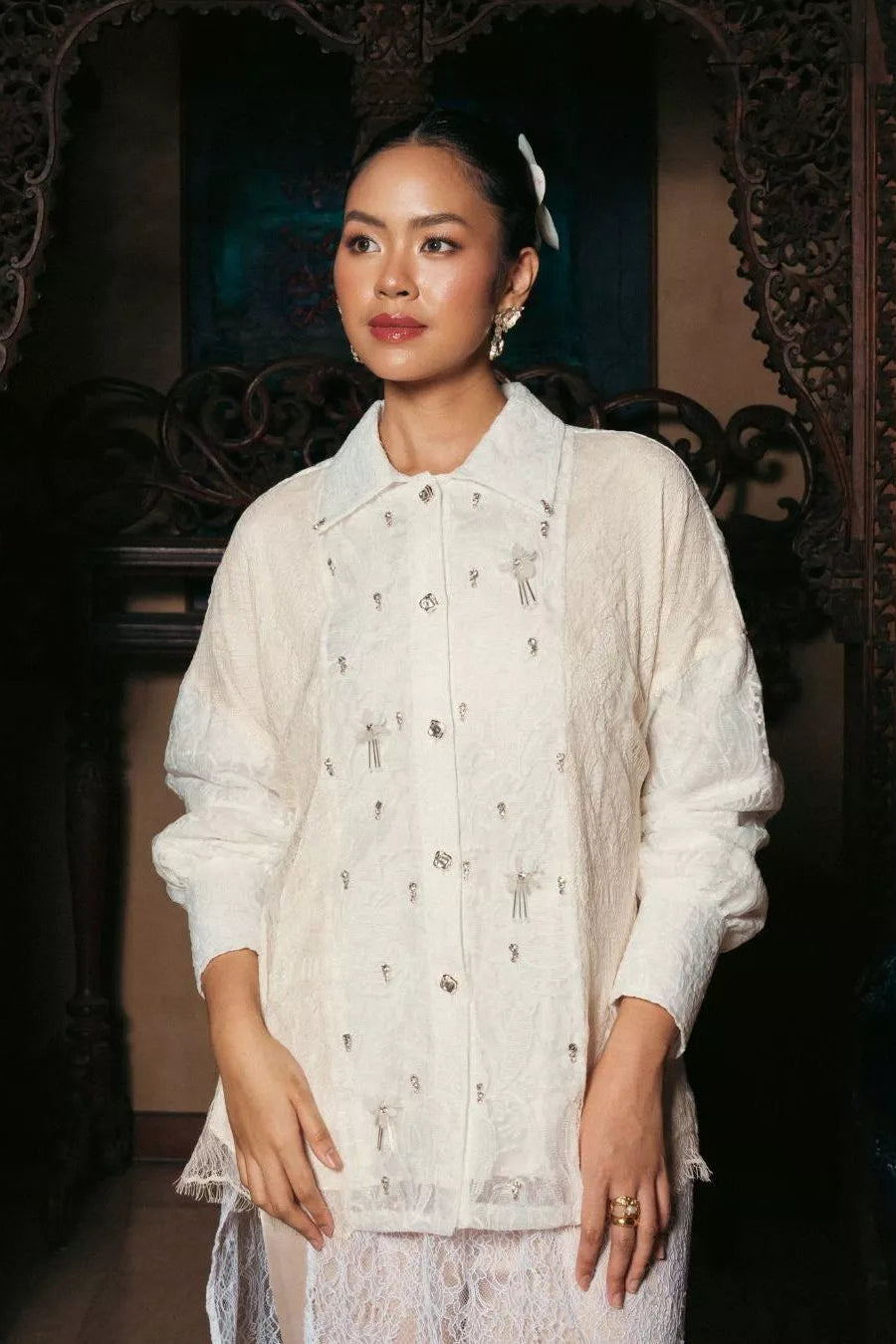 Woman wearing a white embroidered top by LR Studio in an ornate setting