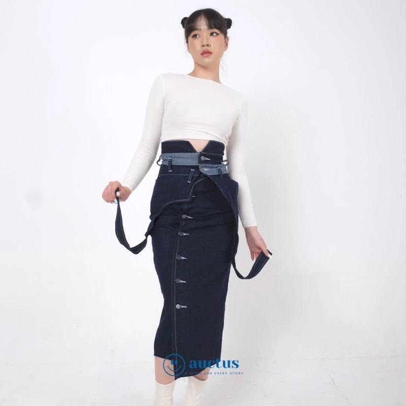 A person wearing a dark blue denim skirt with a high waist and long length, paired with a white long-sleeve top.