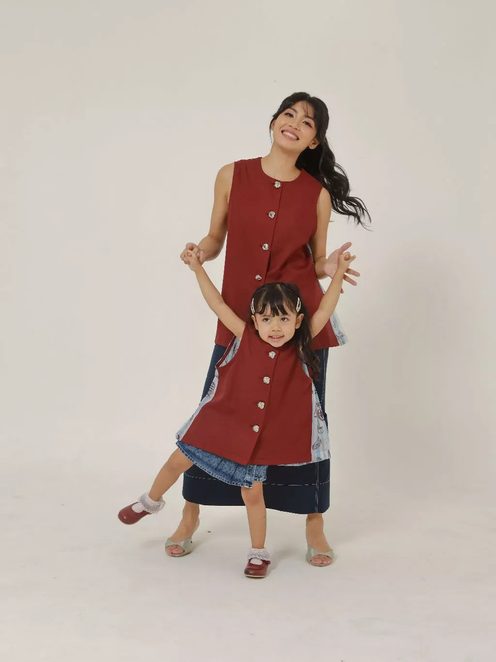 Two people wearing matching red sleeveless button-up vest on a white background