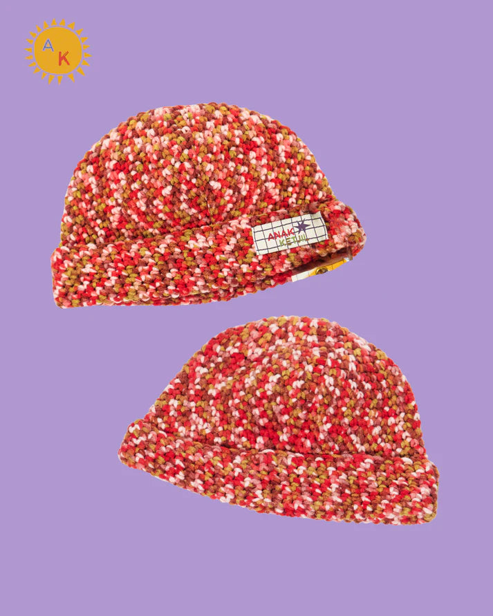 Two red and white speckled beanies hat on a purple background with a brand logo.