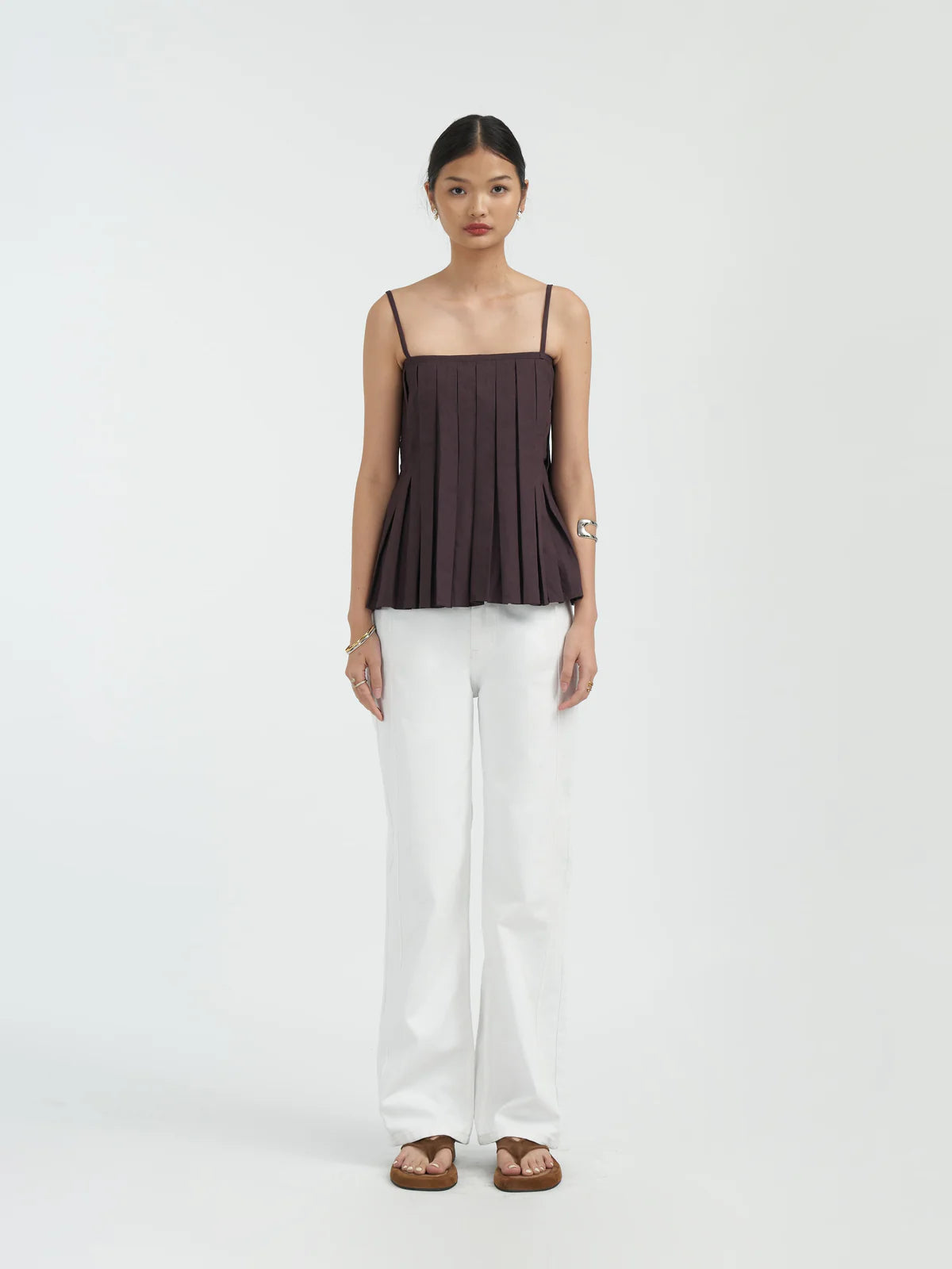 Woman wearing a dark brown Holy Tank by Acheté de Nous and white pants on a white background