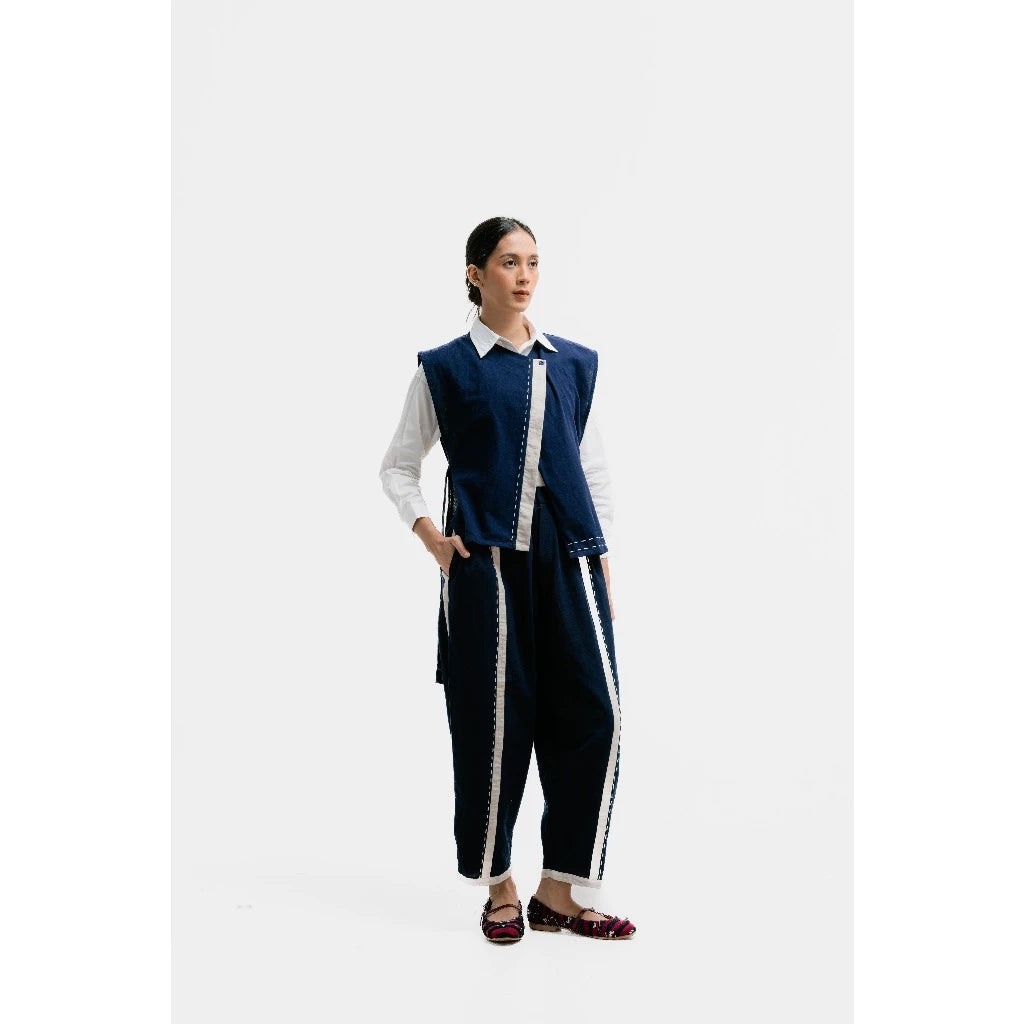 Person wearing a navy vest and pants with white trim on a white background