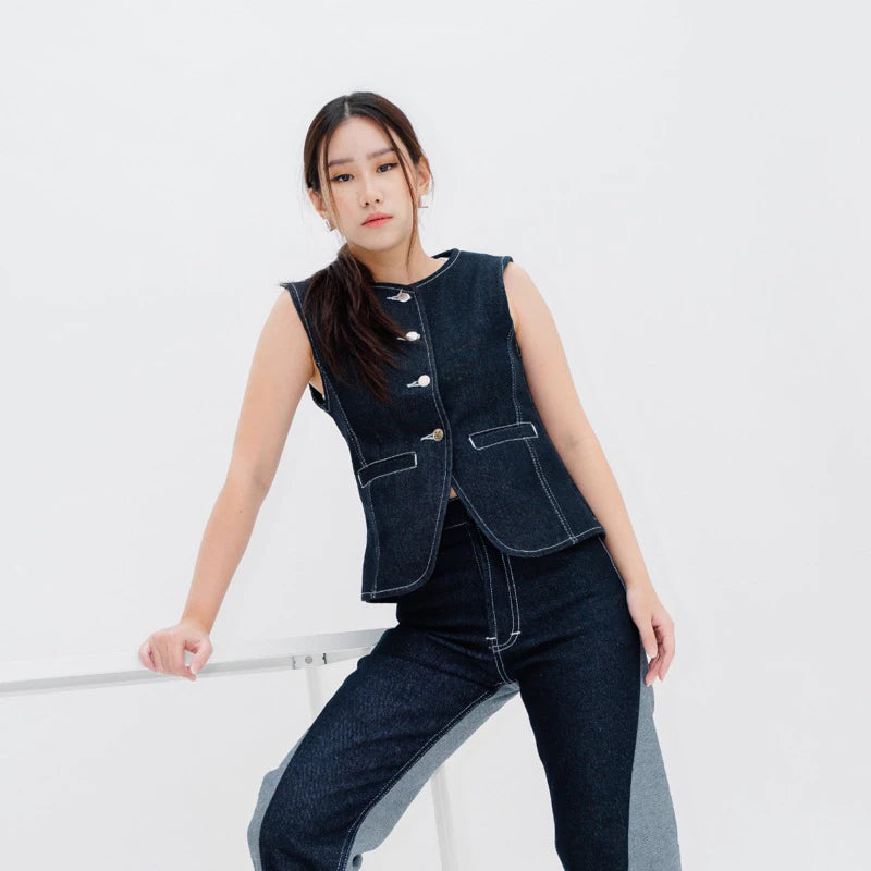 A woman posing in Jemma Button Vest Denim Top, a dark blue denim button vest, and matching jeans.