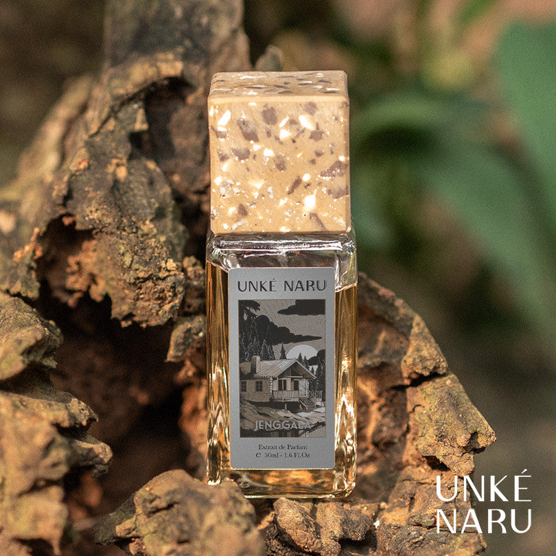 A bottle of Jenggala perfume by UNKE NARU placed on a wooden surface with a blurred background.