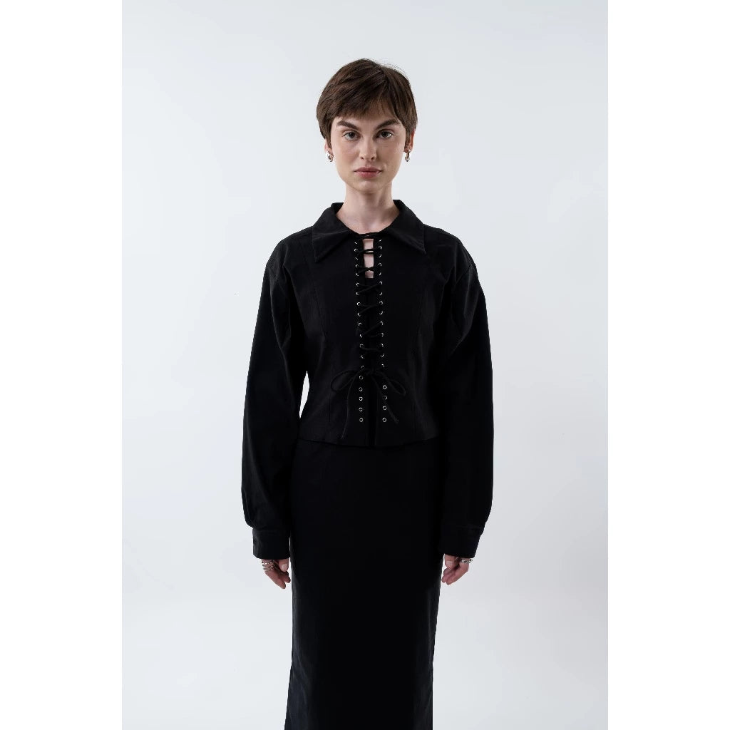 Person wearing a black jacket by Morningsol with lace-up front and black skirt on a white background