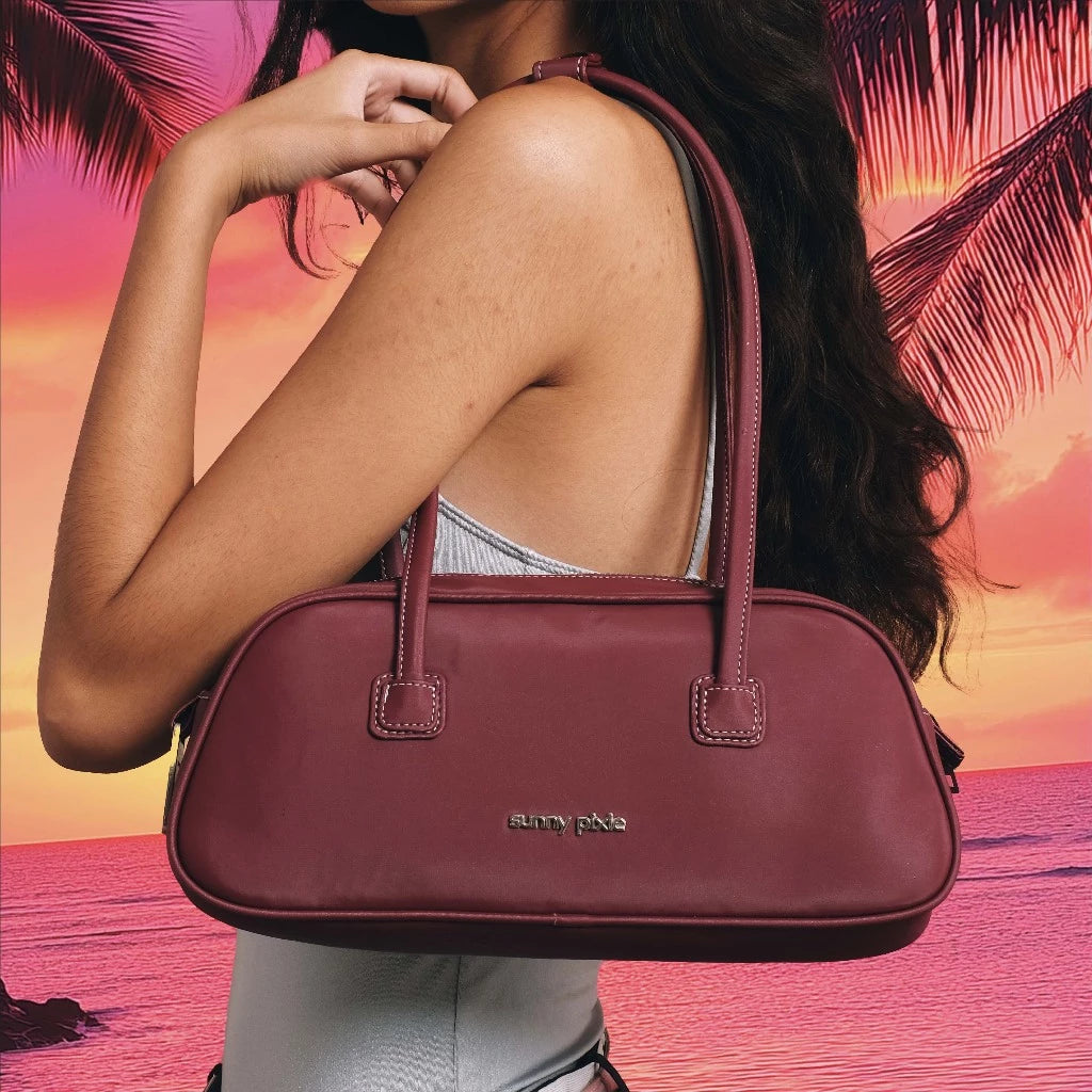 A person holding a red Juju Bag by Sunny Pixie with silver metallic hardware, the bag has a sleek, futuristic design with two handles.

Seorang wanita memegang tas wanita Juju berwarna merah dari Sunny Pixie dengan aksesori logam perak, tas tersebut memiliki desain yang ramping dan futuristik dengan dua pegangan.