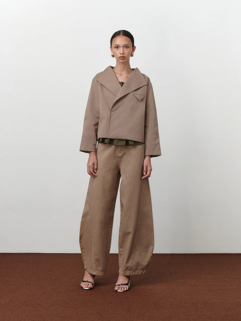 Model wearing a beige Leo Trench Coat bt Acheté de Nous and pants on a white background