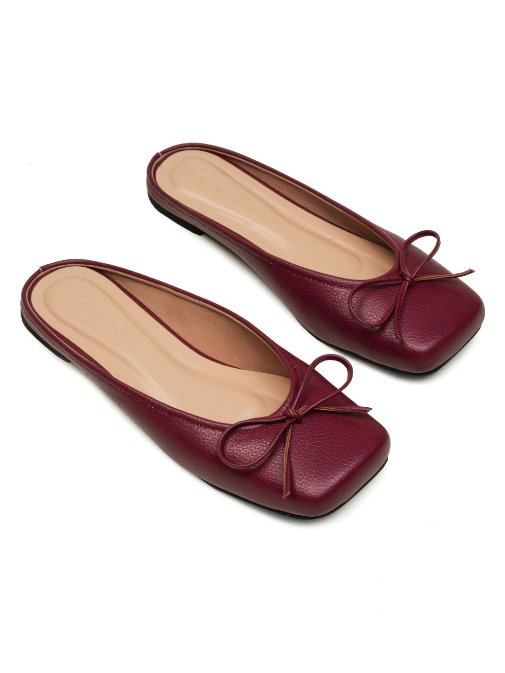 Pair of maroon flat shoes with a bow details on a white background