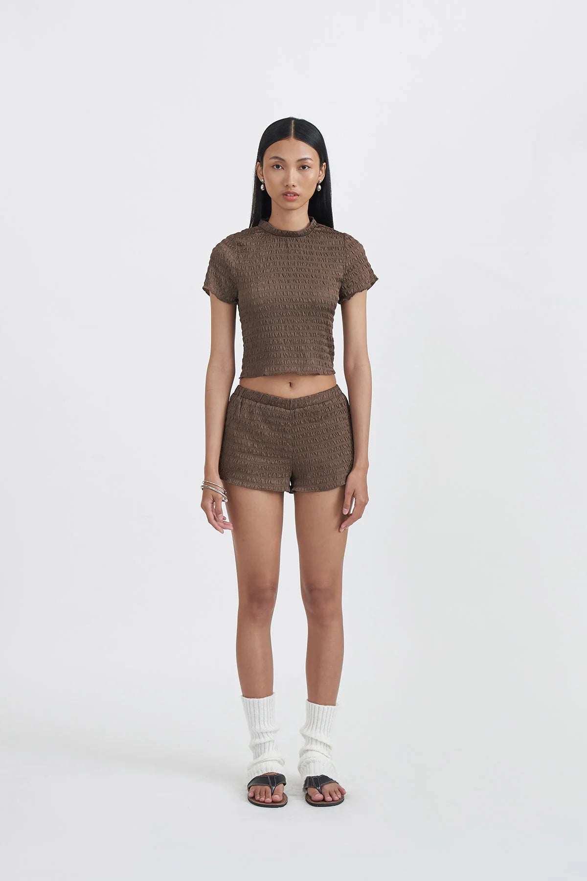 Woman wearing a brown textured top by Callie Cotton and shorts set on a white background