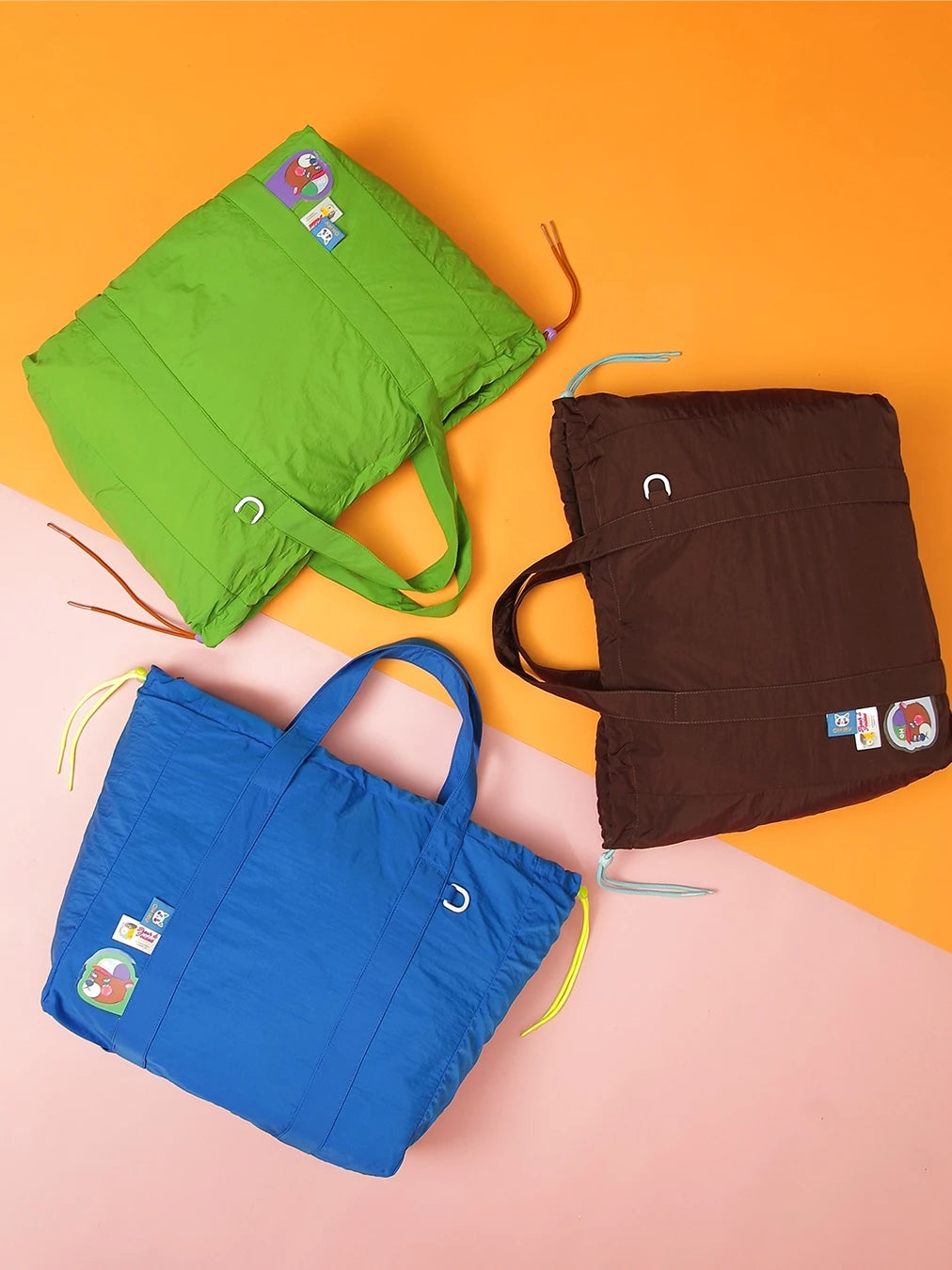Three bags by Oh.Irv in green, blue, and brown on a pink and orange gradient background