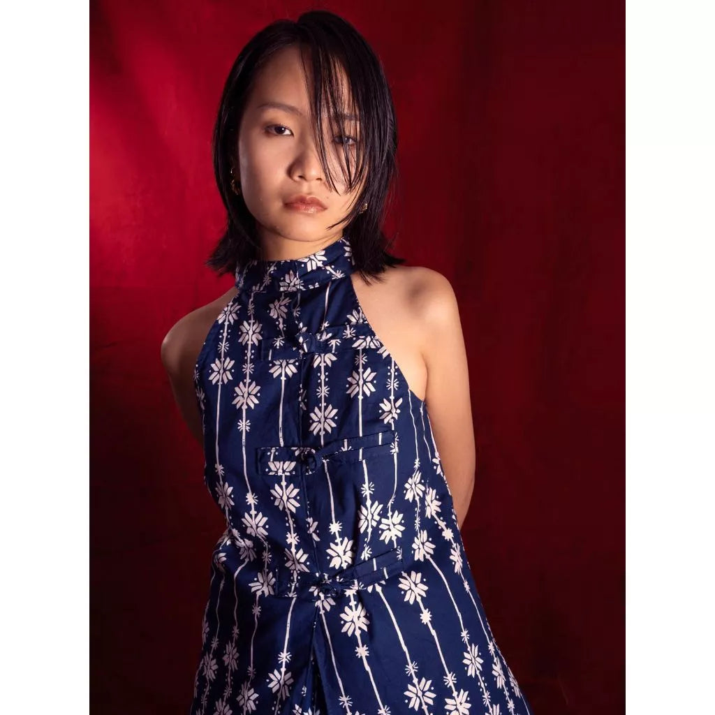 Woman wearing a blue floral sleeveless batik by Manikan against a red background
