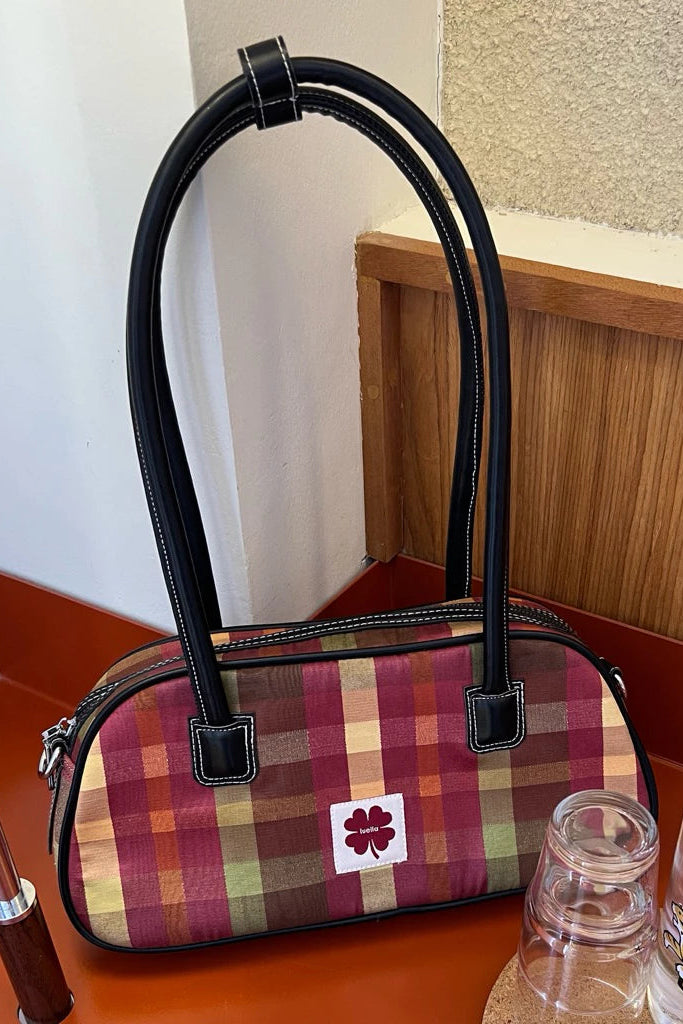 Plaid shoulder bag by Luella with black handle on a wooden surface