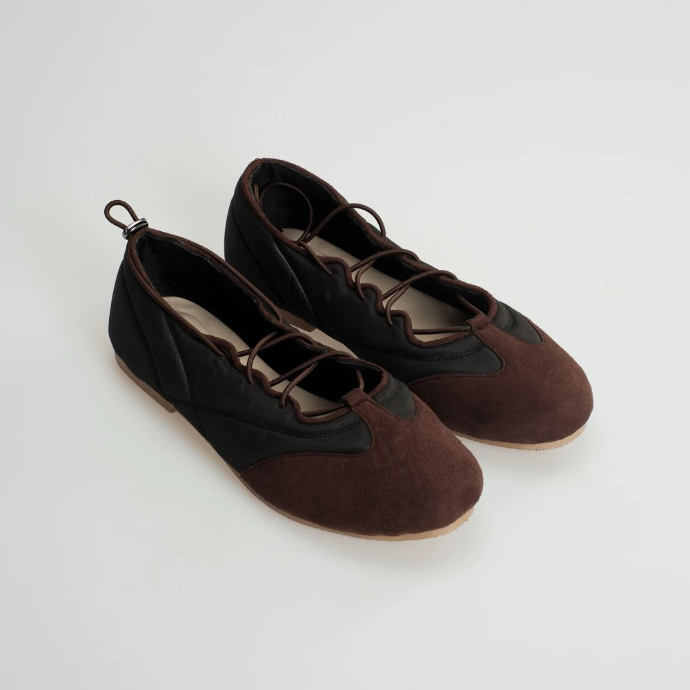 Pair of brown and black flatshoes on a light gray background