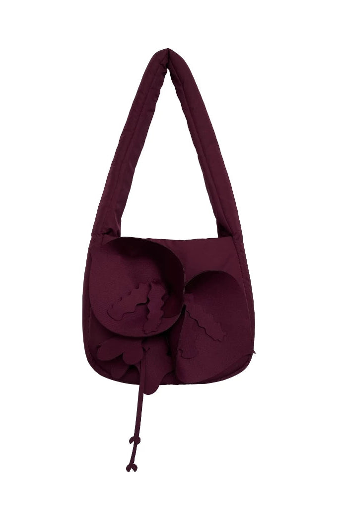A dark burgundy shoulder bag by Hunting Fields with a unique sculptural, layered flower-like design on the front and a single integrated shoulder strap, shown against a plain white background.