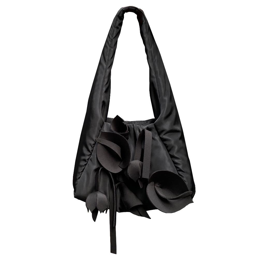 A black tote bag by Hunting Fields with a shoulder strap and multiple fringe details on the flap.