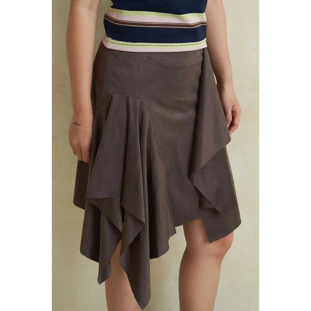 Person wearing a grey ruffled skirt and a striped top on a plain background