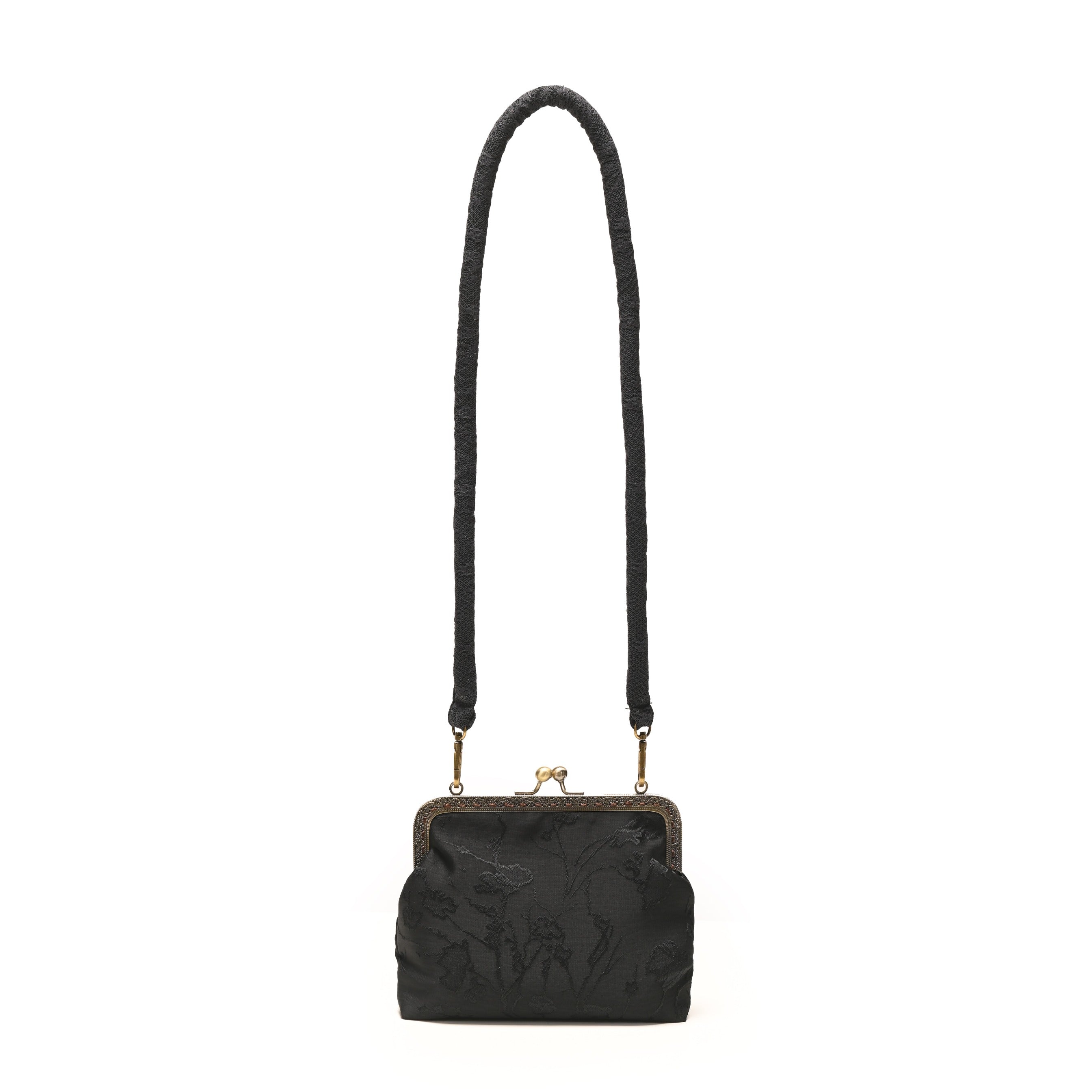 Elegant black women’s bag with a vintage clasp frame, long braided strap, and subtle embossed floral pattern. The antique gold metal details add a refined and timeless charm to this women’s bag.

Tas wanita hitam bergaya vintage dengan bingkai kait klasik, tali panjang anyaman, dan motif bunga timbul yang elegan. Detail logam berwarna emas antik memberikan sentuhan klasik dan menawan pada tas wanita ini.