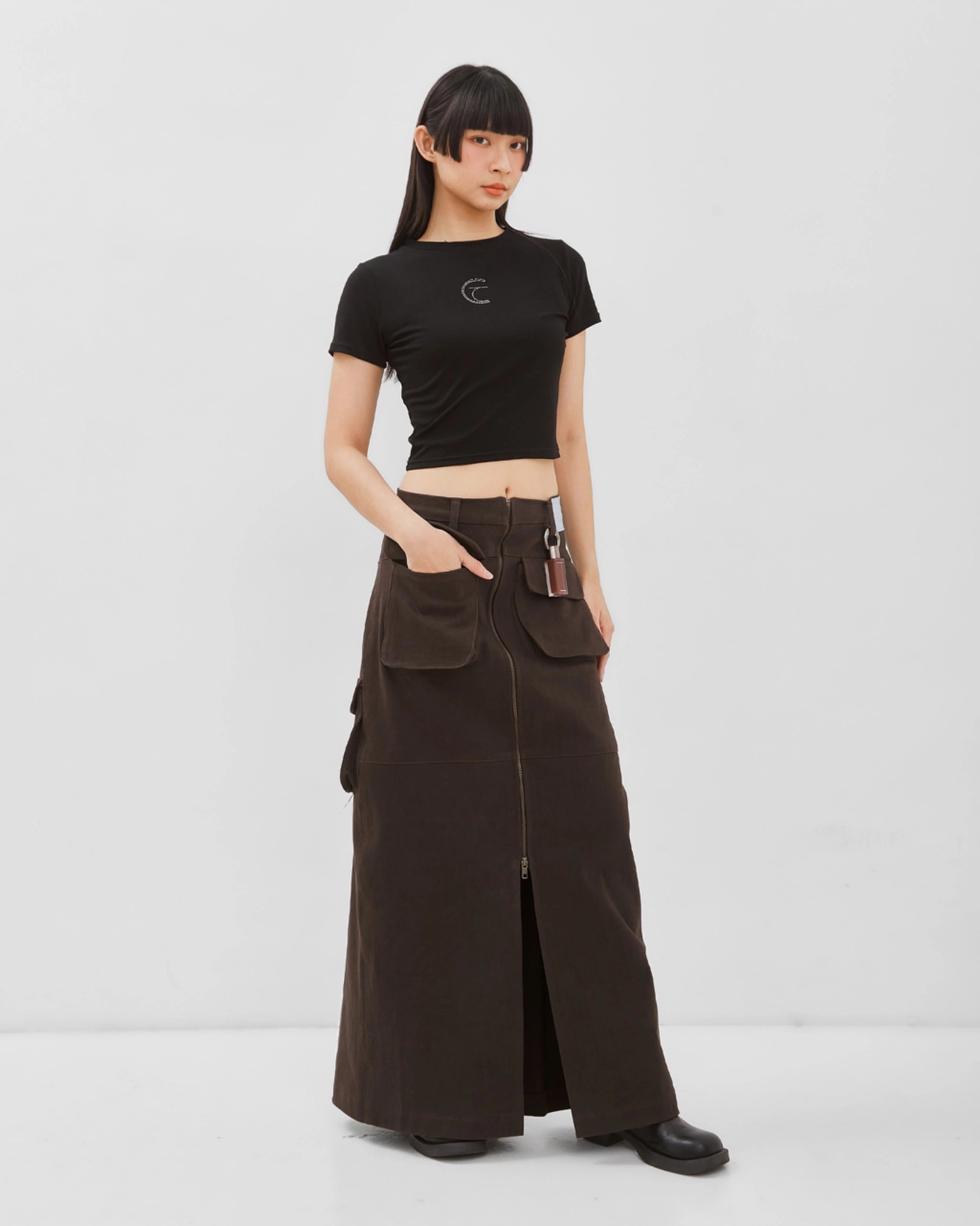 Person wearing a black crop top and brown cargo skirt from Catha on a white background