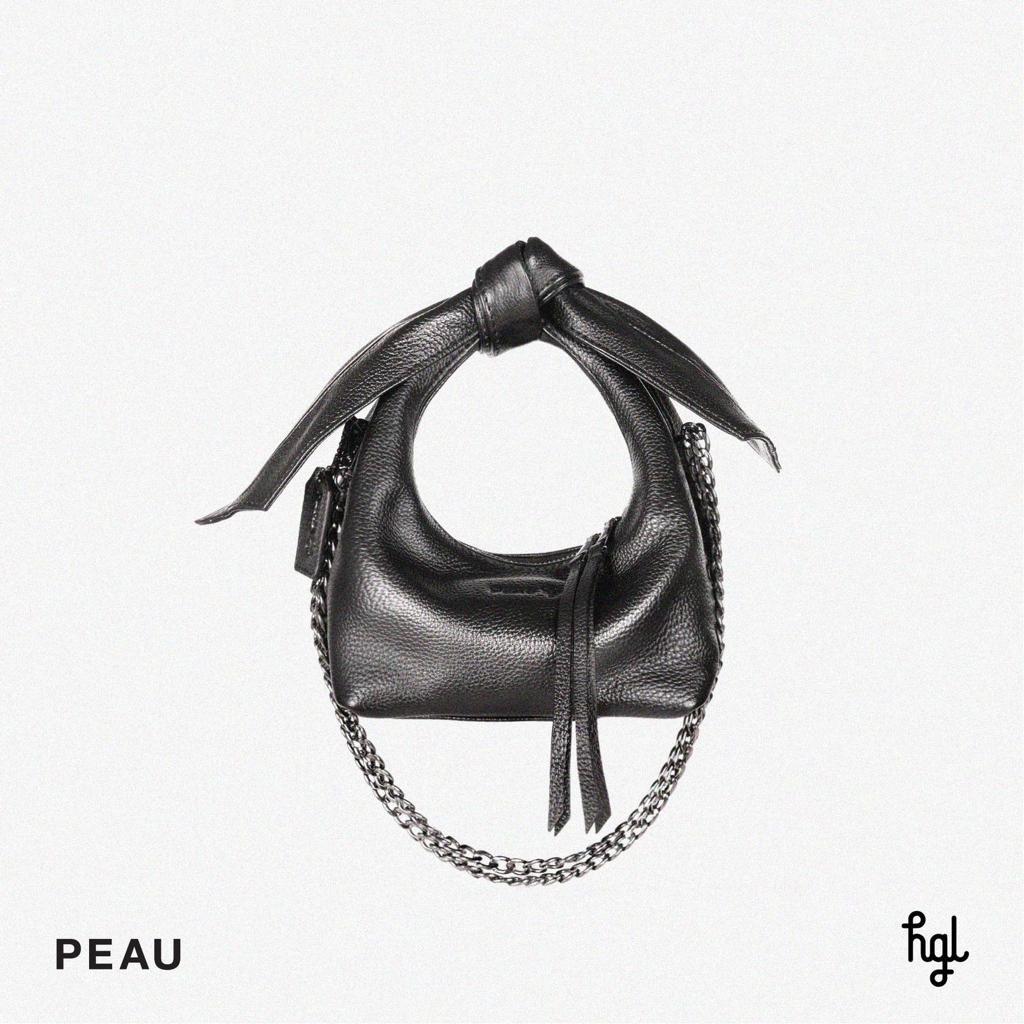 Black leather handbag with a zipper closure and chain strap, displayed against a white background with the brand name 'PEAU x HGL' visible.

Tas tangan wanita berbahan kulit berwarna hitam dengan penutup resleting dan tali rantai, ditampilkan di latar belakang putih dengan nama merek ‘PEAU x HGL’