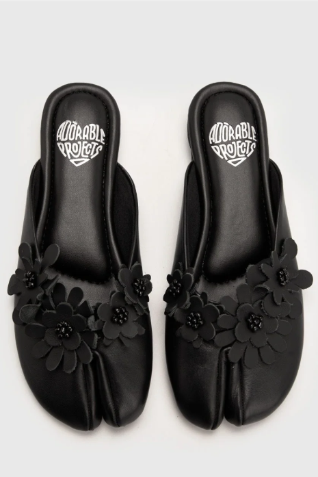 Black floral sandals with 'Adorable Projects' logo on a light gray background