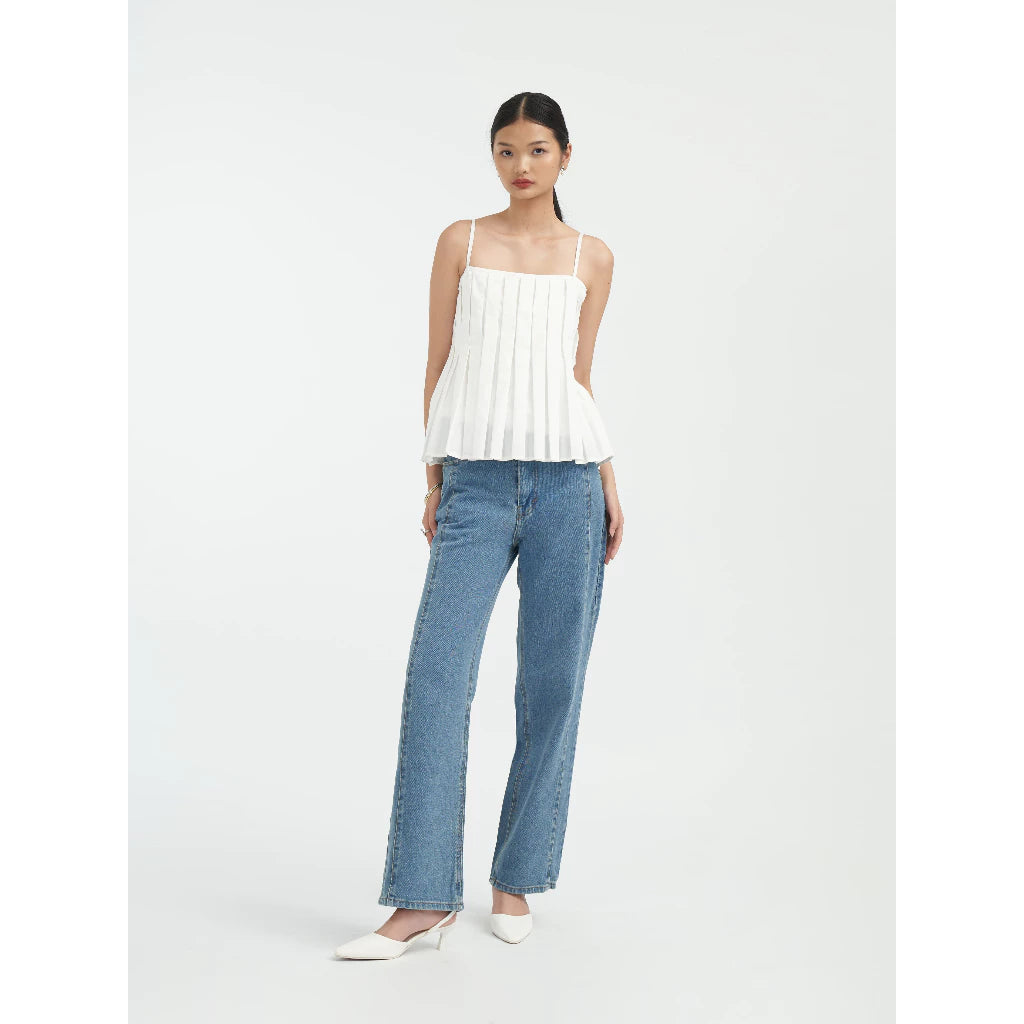 Woman wearing a white pleated top and blue jeans by Achete de Nous on a white background
