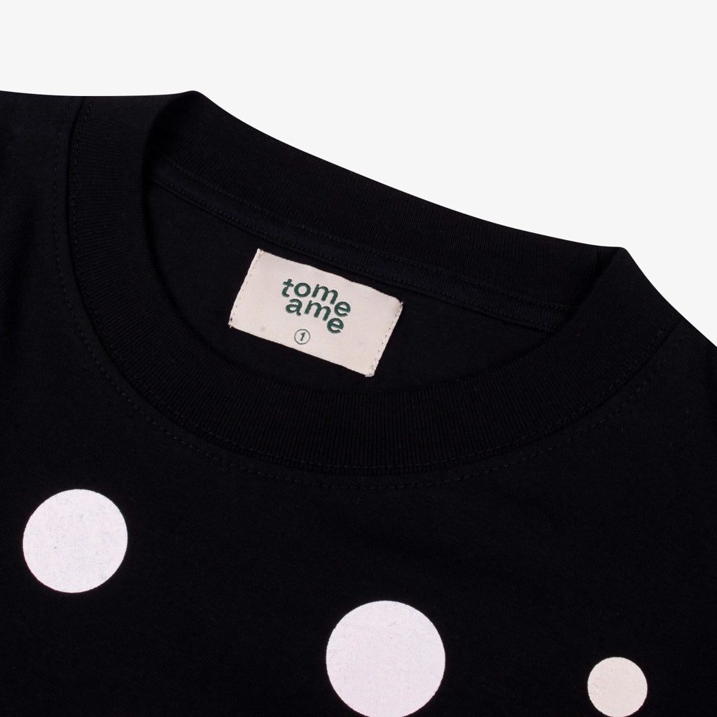 Black t-shirt with white polka dots and 'tome ame' label on a white background