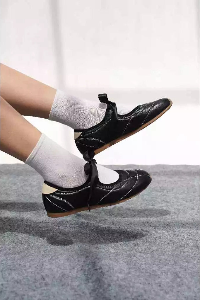 Black flatshoes worn with white socks on a light gray background

Flat shoes wanita berwarna hitam yang dikenakan dengan kaus kaki putih di atas latar belakang abu-abu muda