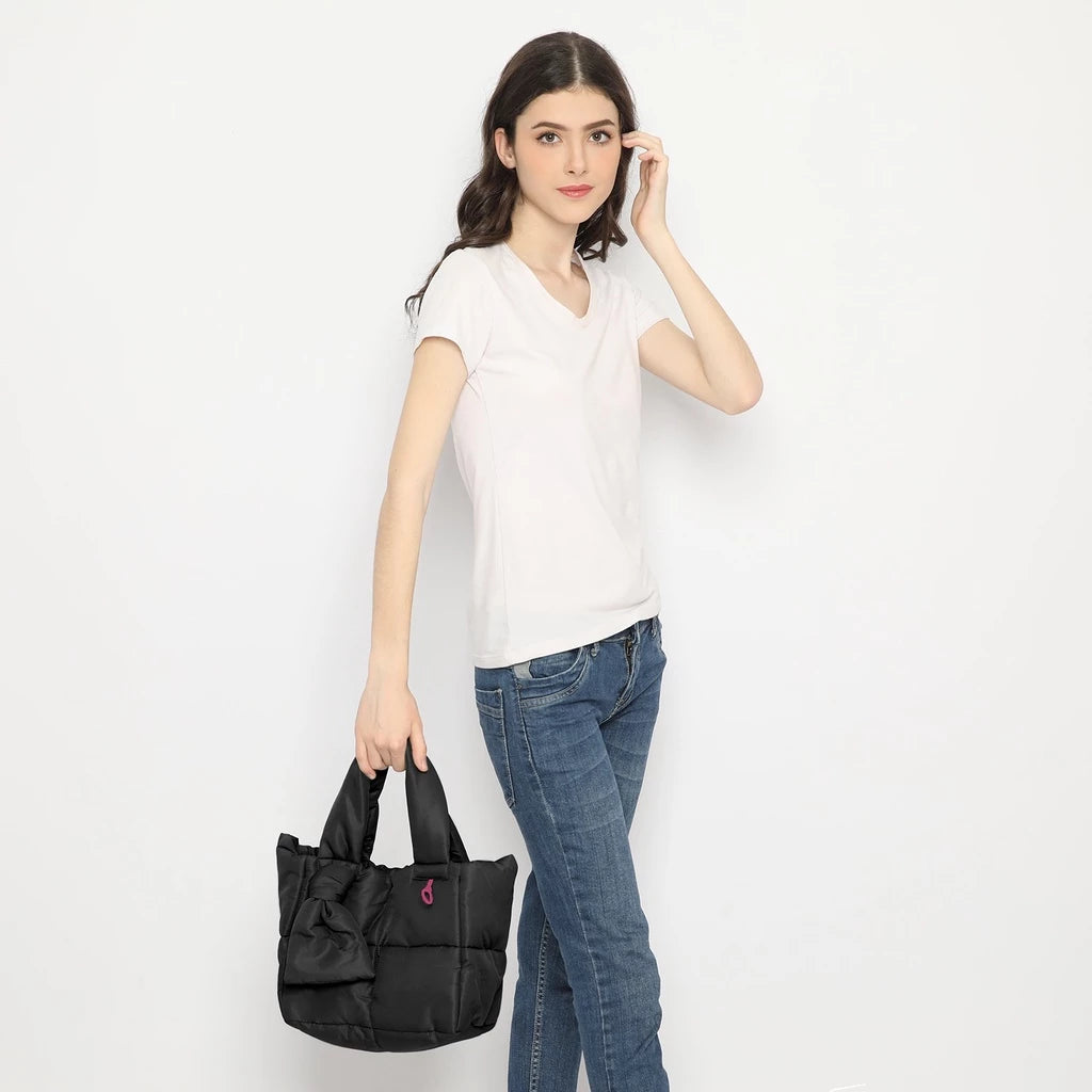 Woman holding a black handbag by Hunting Fields against a white background