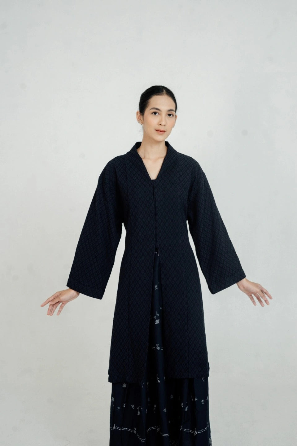 Woman wearing a long navy tunic by Damakara against a plain background