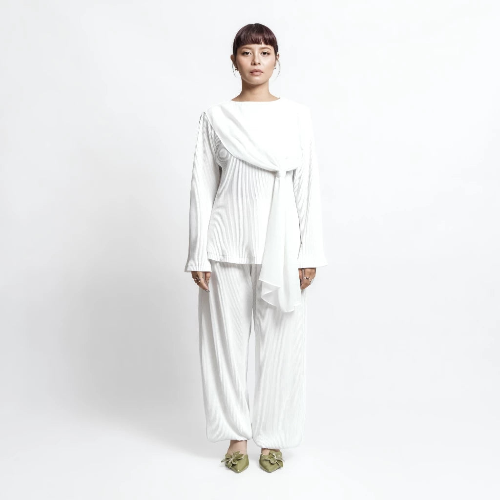 Person wearing a white outfit by Isoos Studios with a scarf on a plain background