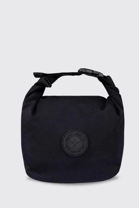 A black roll-top lunch bag by Exsport Bag with a black strap and buckle, featuring a circular black logo patch on the front, set against a light gray background.