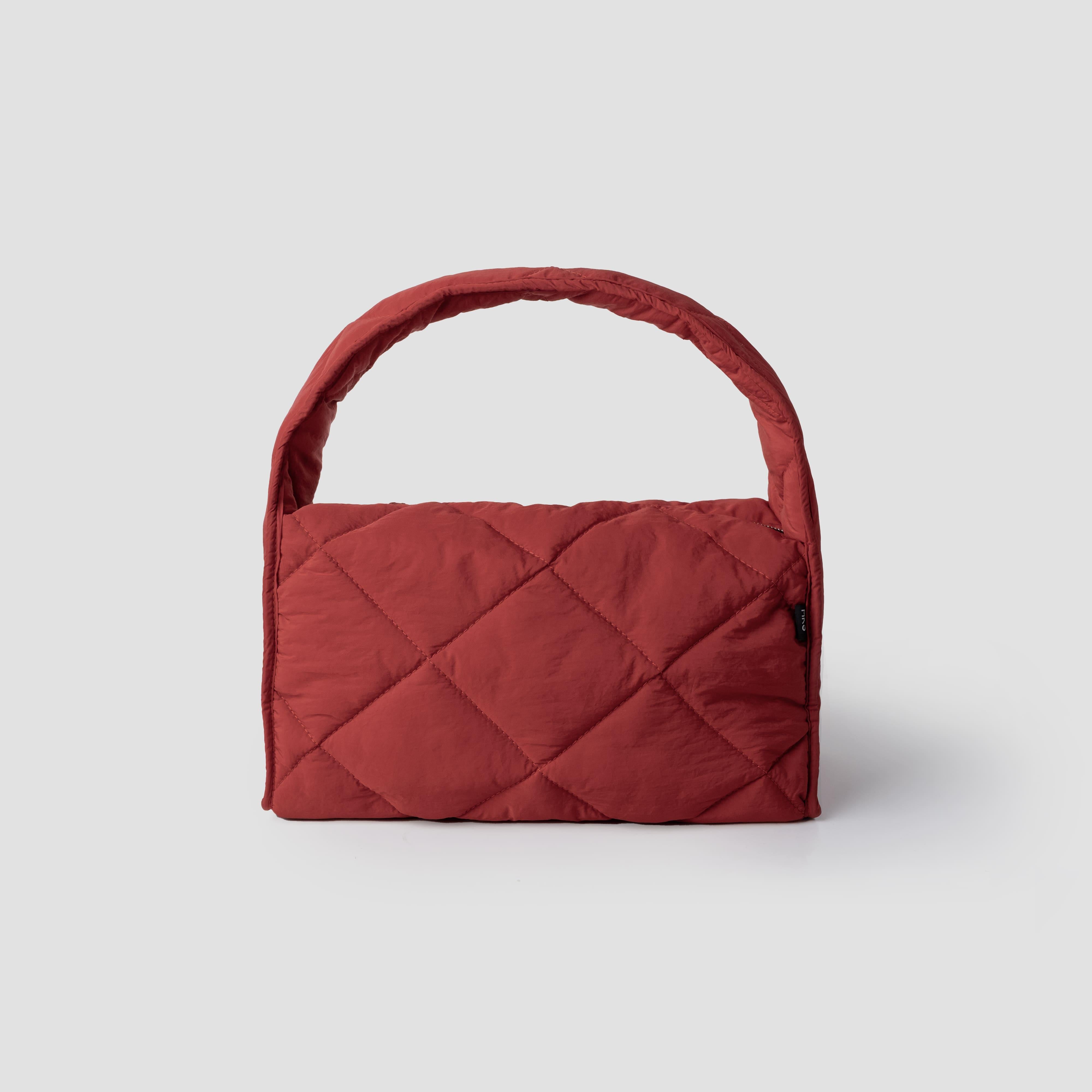 Red quilted women's handbag on a light gray background.

Tas tangan wanita berlapis berwarna merah dengan latar belakang abu-abu muda.