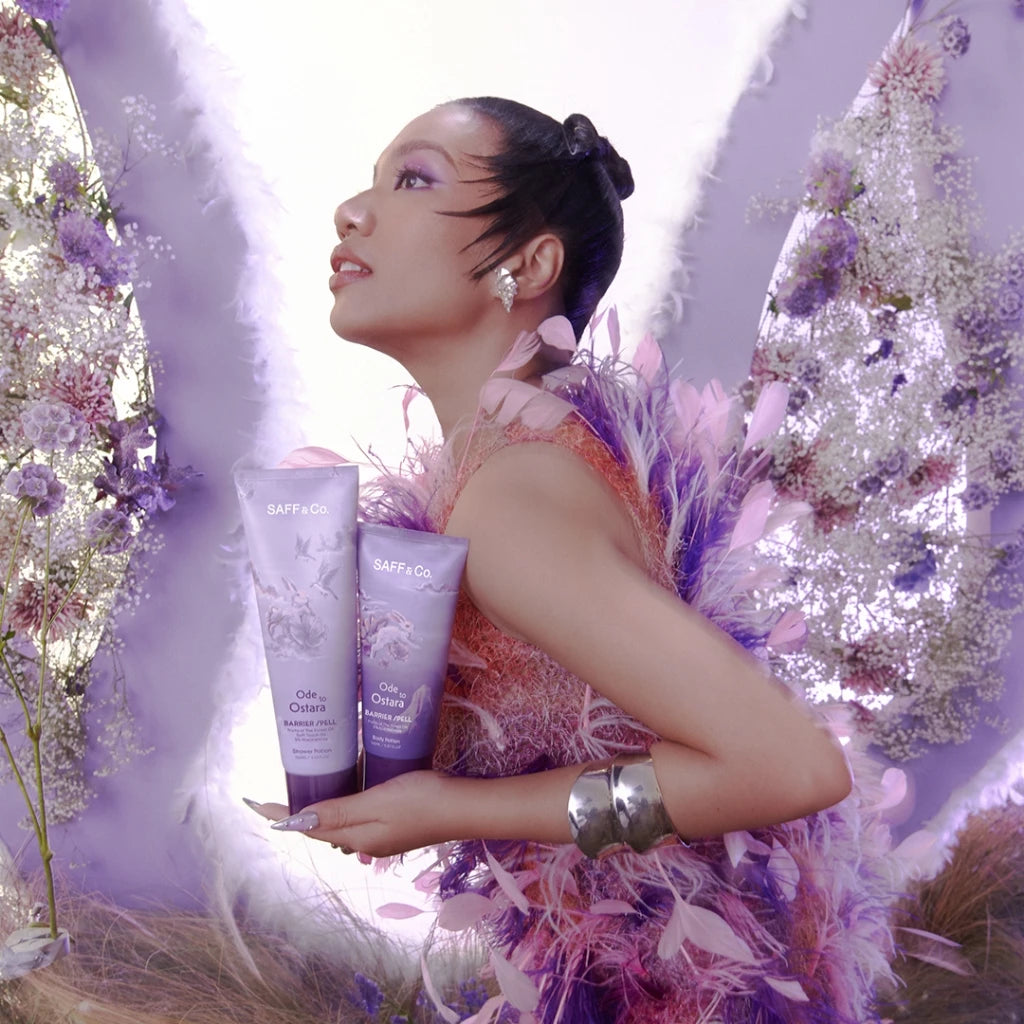 Woman in a decorative setting holding two tubes of Saff & Co. Body Potion