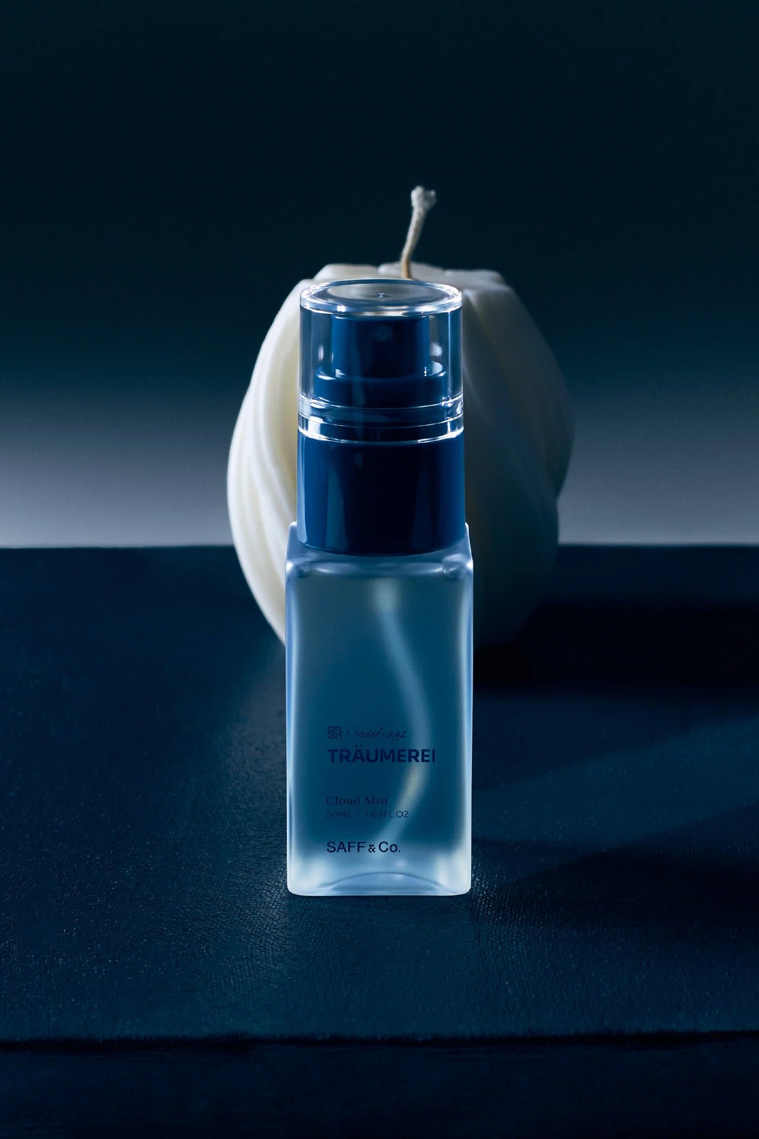 Blue body mist bottle by Saff & Co with a white apple on a dark surface