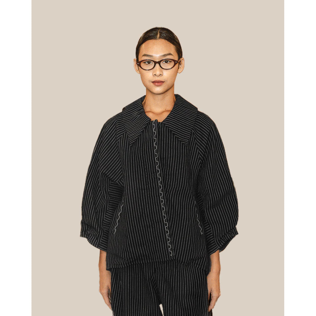 Person wearing a navy and white striped jacket by Damakara on a beige background