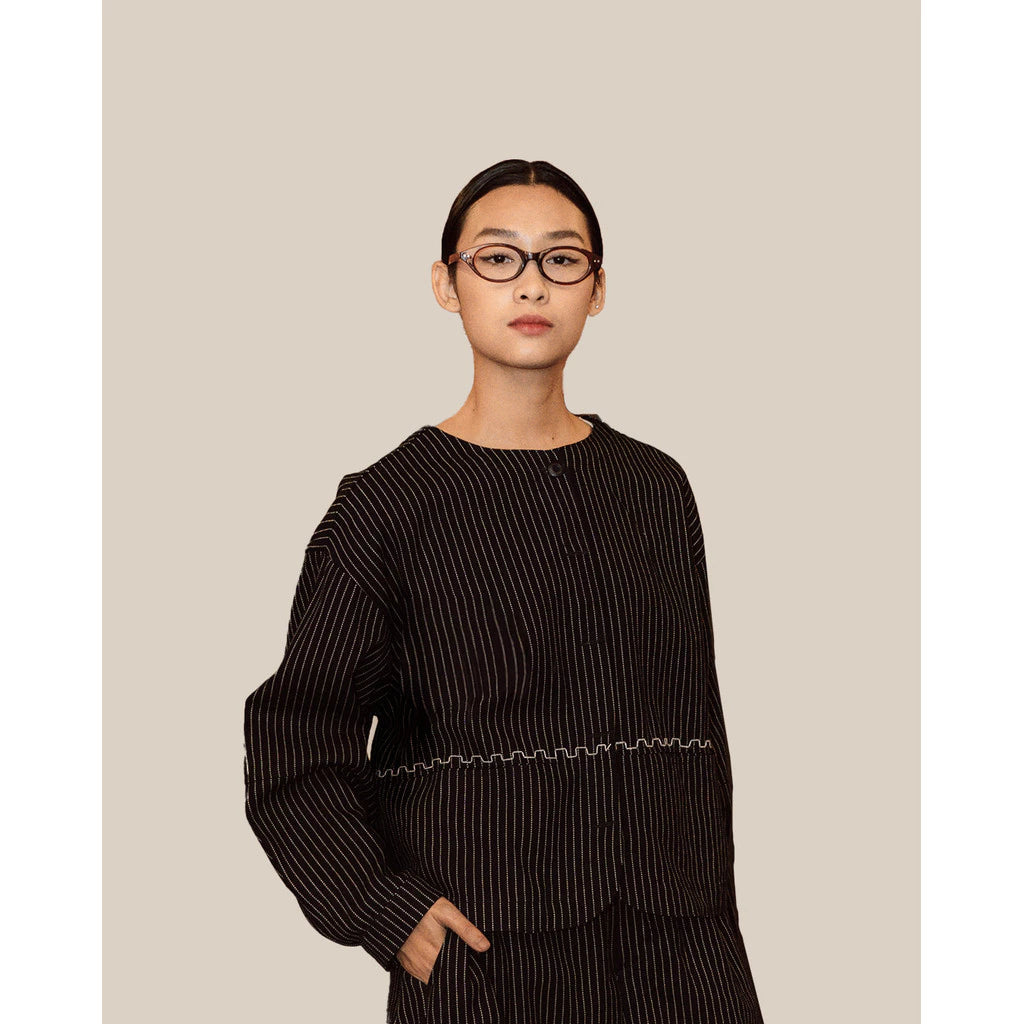 Person wearing a navy striped sweater by Damakara against a beige background