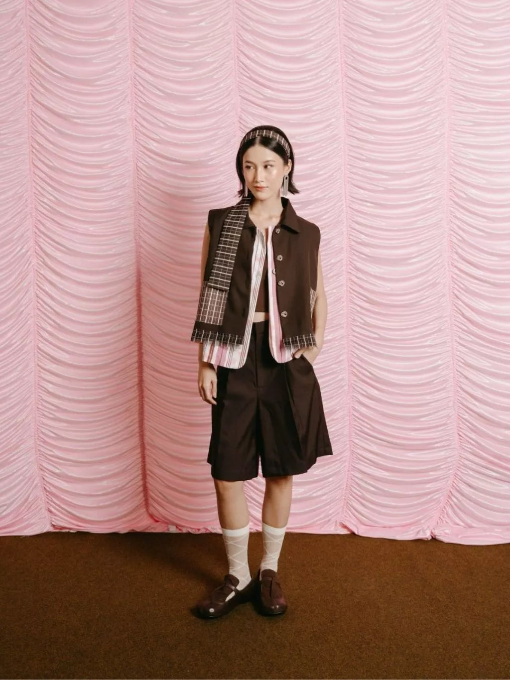 Person wearing a brown and pink vest by LR Studio with a pink textured backdrop