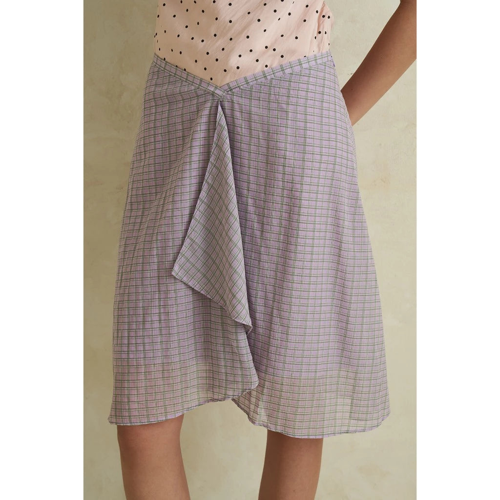 Person wearing a purple checkered skirt with a plain background