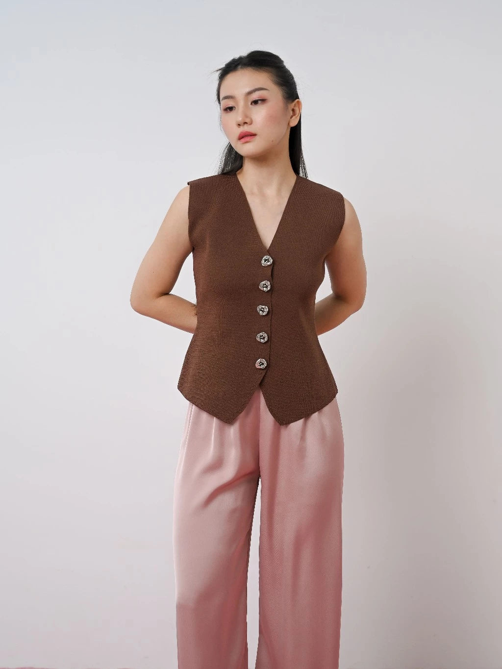 Woman wearing a brown vest by LR Studio and pink pants against a plain background