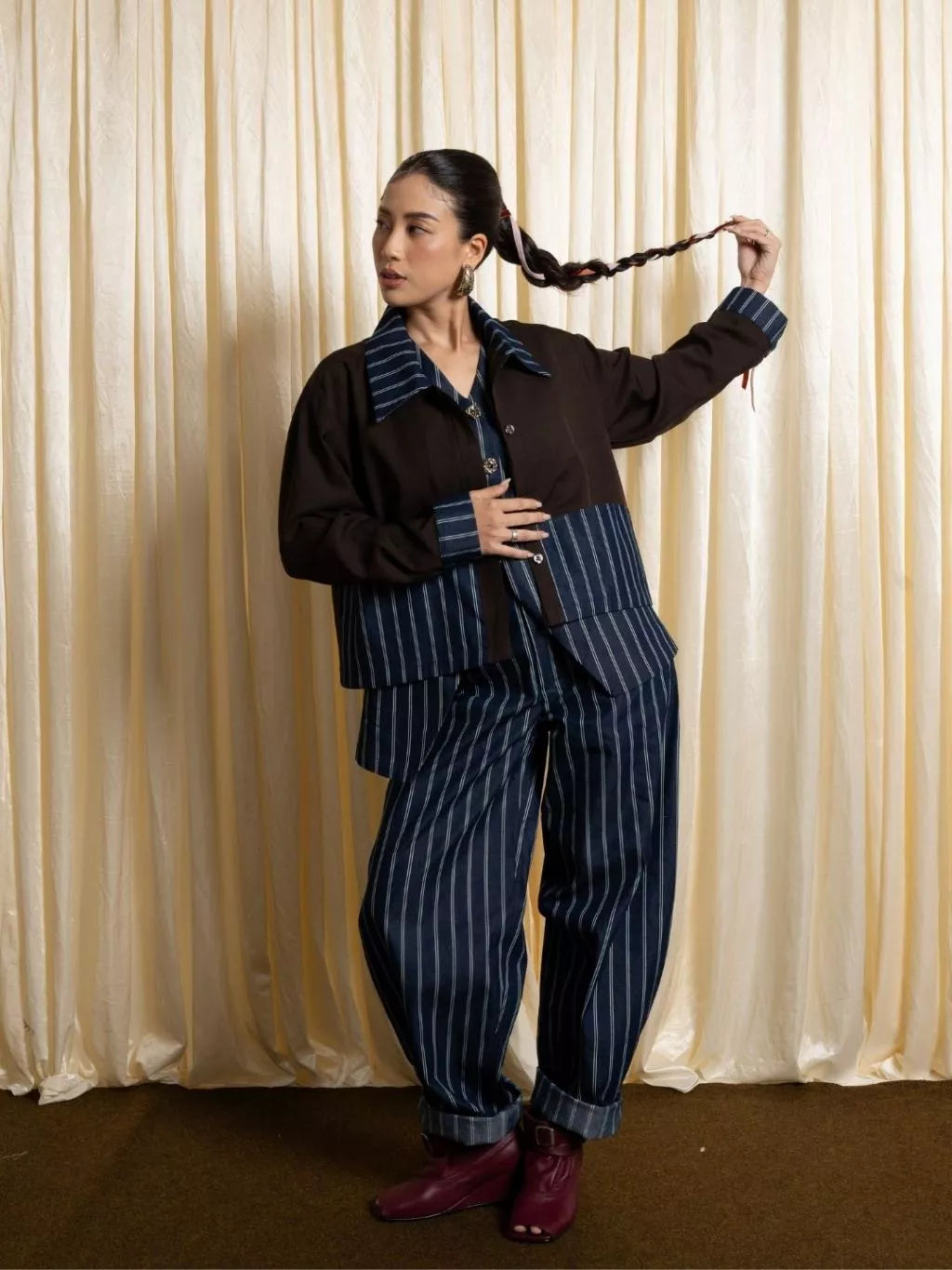 Person wearing a brown and blue striped jacket by LR Studio against a beige curtain background