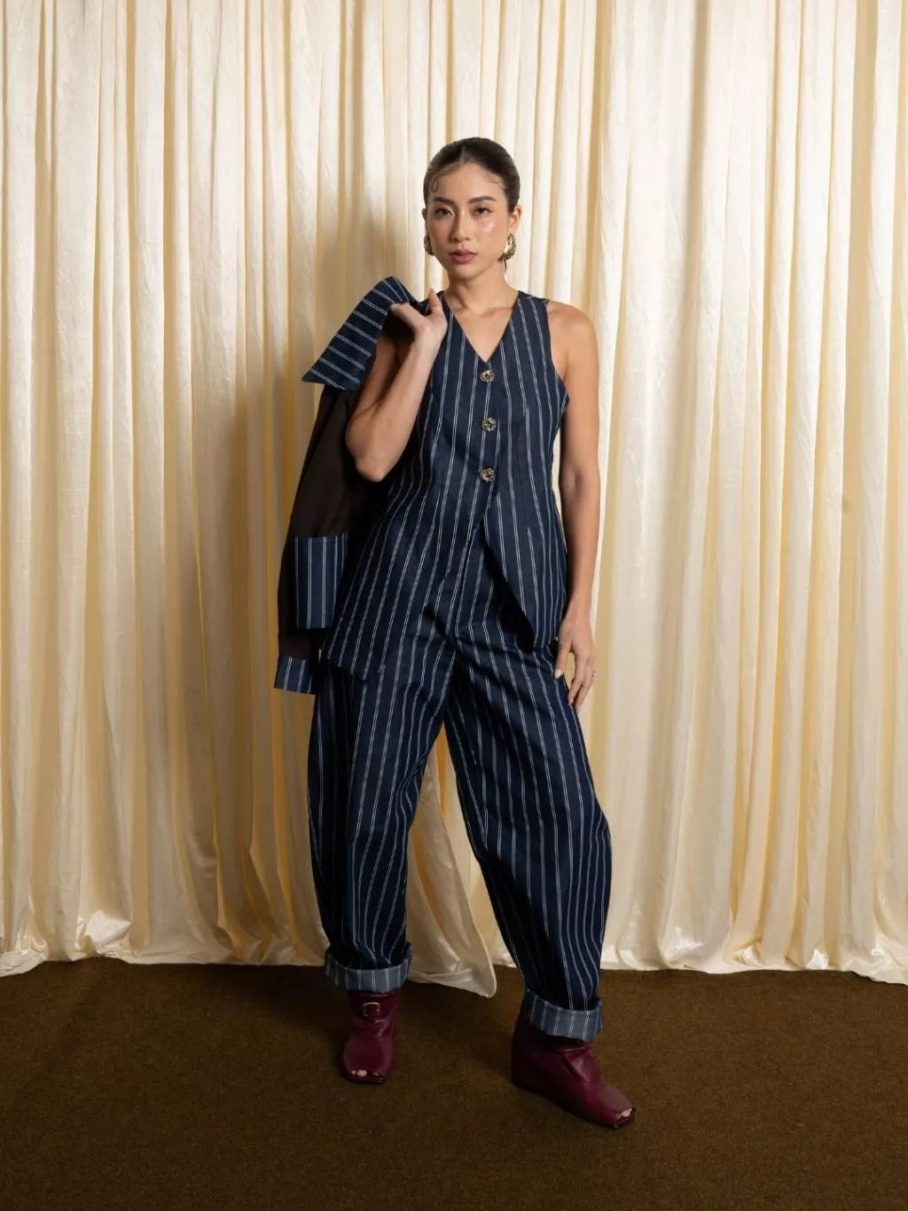 Person wearing a navy pinstripe vest by LR Studio against a beige curtain background