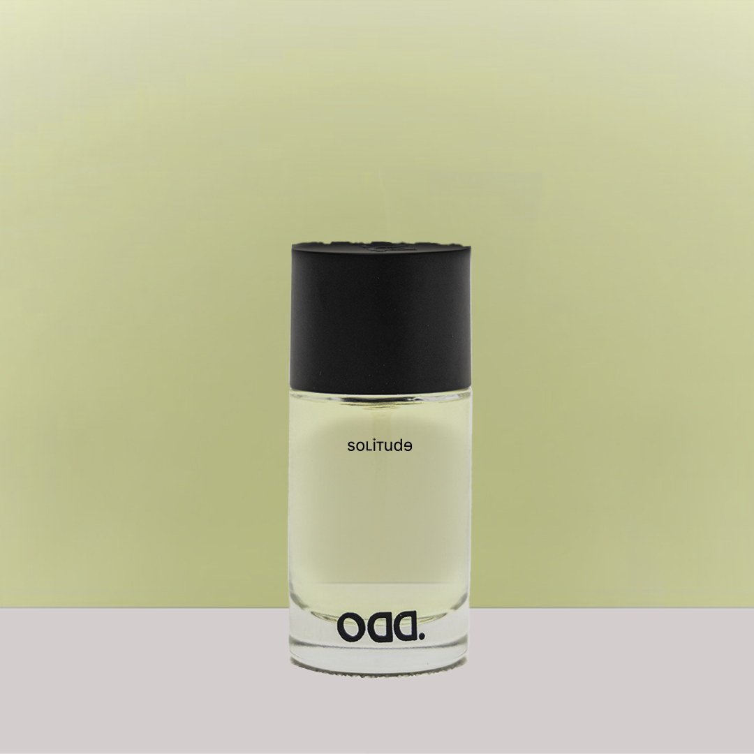 A bottle of 'Solitude' perfume with a black cap, labeled with the brand 'ODD' against a yellow background.