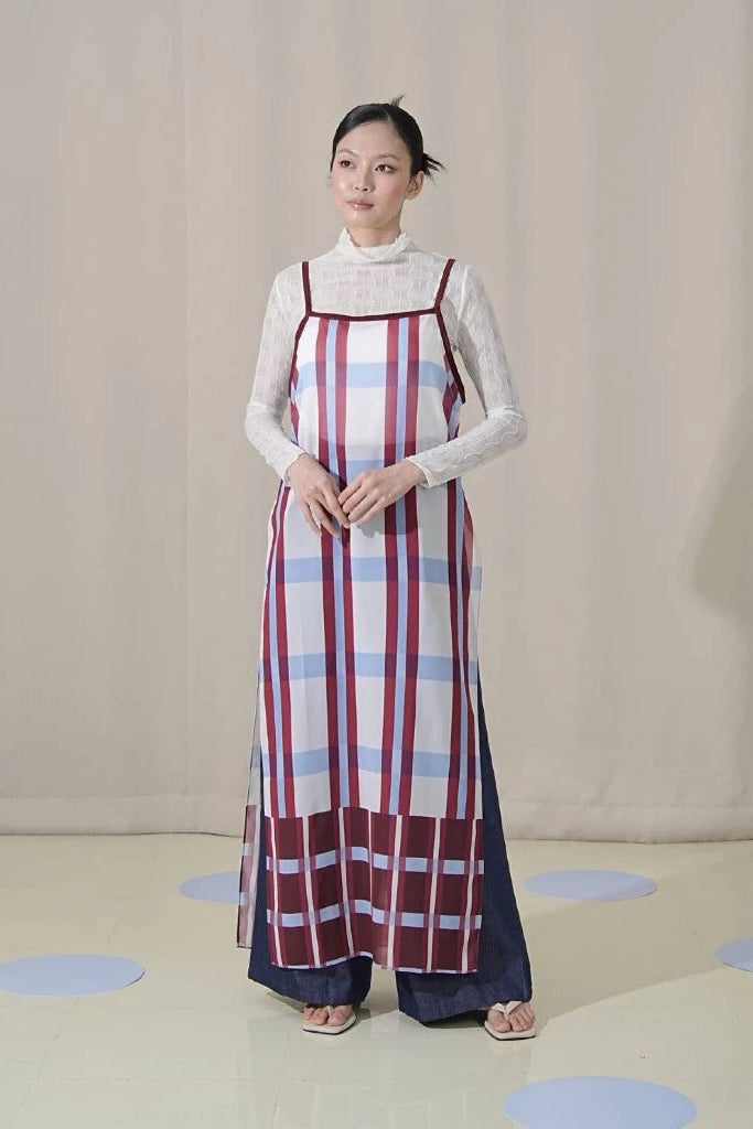 Woman wearing a long, patterned dress by Tuff Puff over a white blouse against a plain background