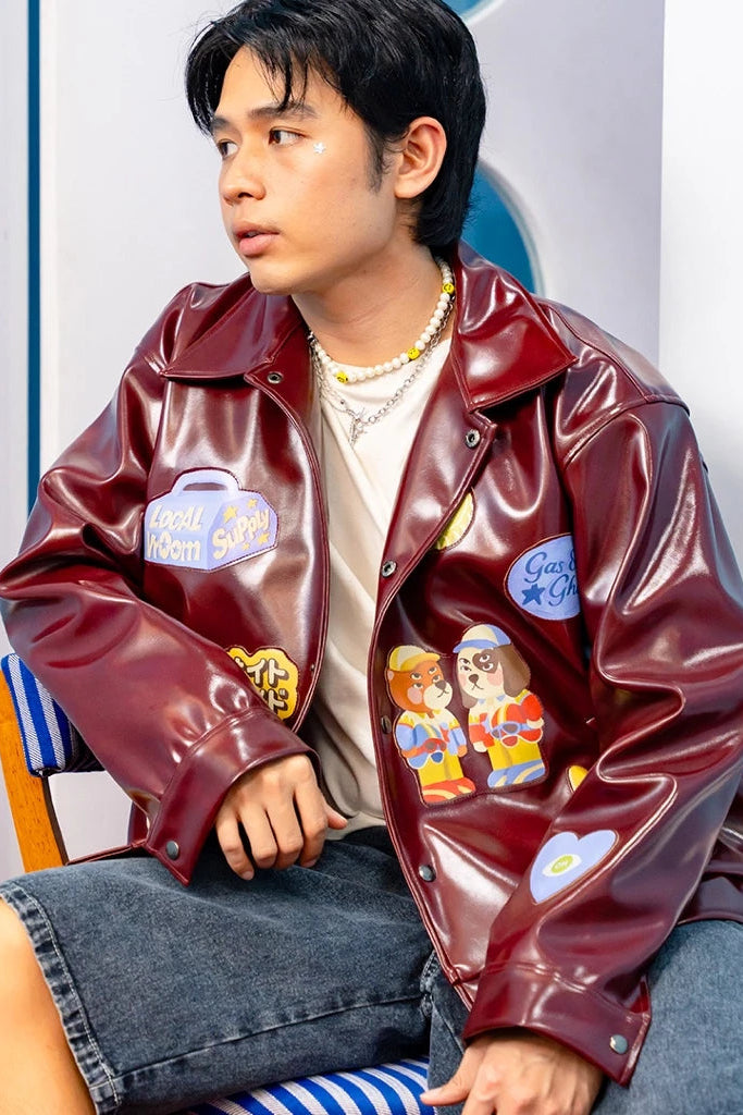 Person wearing a maroon leather jacket with patches by oh.irv sitting on a colorful chair.