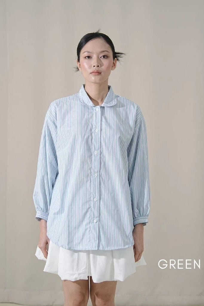 Person wearing a light green striped shirt by Tuff Puff and white mini skirt against a neutral background